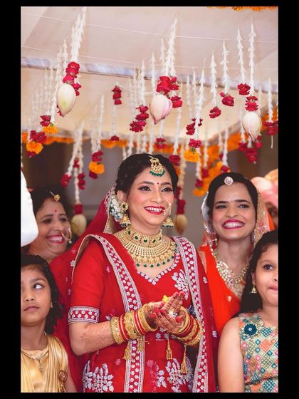 A candid moment of pure joy. This bride is surrounded by her family, her happiness shining through. Her traditional red lehenga and classic bridal makeup were perfect for her Phera ceremony.