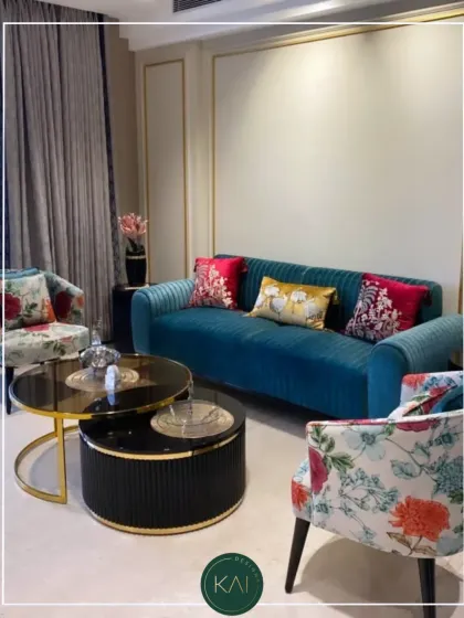We love bringing vibrant personality into a room with custom upholstery. This living room set features a bold, channel-tufted teal sofa paired with elegant armchairs in a classic floral print, all centered around a modern, multi-tiered coffee table.