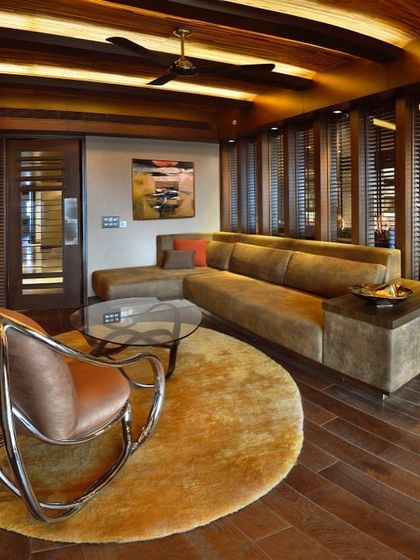 A cozy den in the Magnolias project, featuring a comfortable sectional sofa and a unique rocking chair. The wood-slatted walls and ceiling create a warm, cabin-like feel.