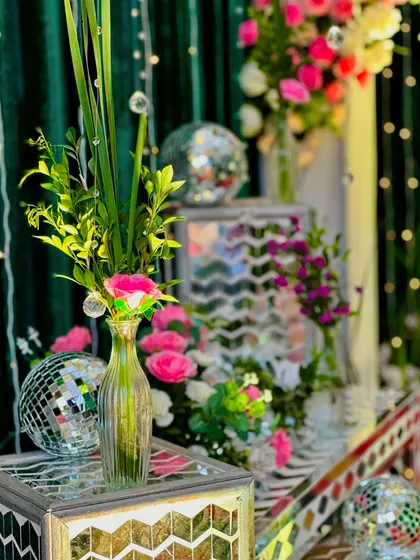 A close-up of the decor details for a disco-themed Sangeet, showing small mirror balls, fresh flowers, and mirrored furniture.