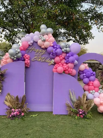 A modern and chic birthday backdrop in purple, accented with a beautiful organic balloon garland in shades of pink, purple, and silver.
