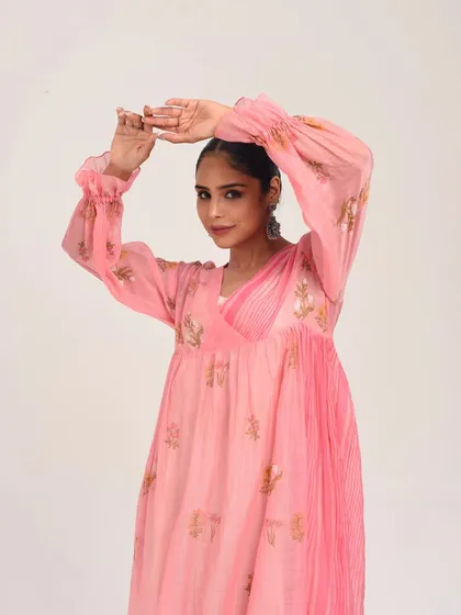 Soft pastel hues for summer charm. This model wears a lovely pink ombre anarkali with pleated details and delicate gold floral motifs.