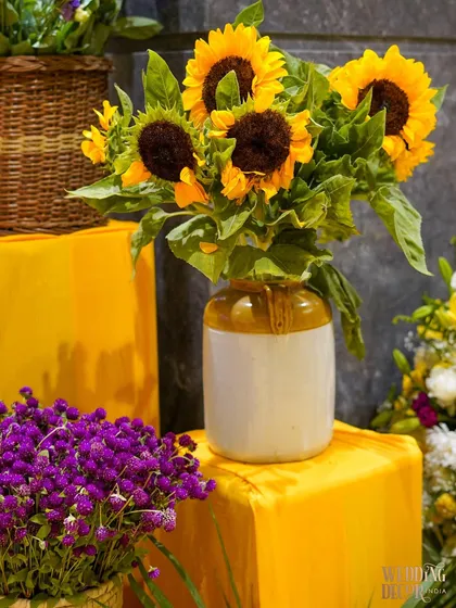 A classic arrangement of sunflowers in a rustic ceramic vase, paired with a bunch of purple flowers. This combination is both cheerful and elegant.