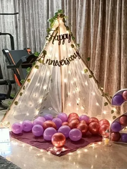 A sweet second-anniversary surprise at home. A canopy tent with fairy lights is set up in the living room, complete with balloons and a light-up number '2'.