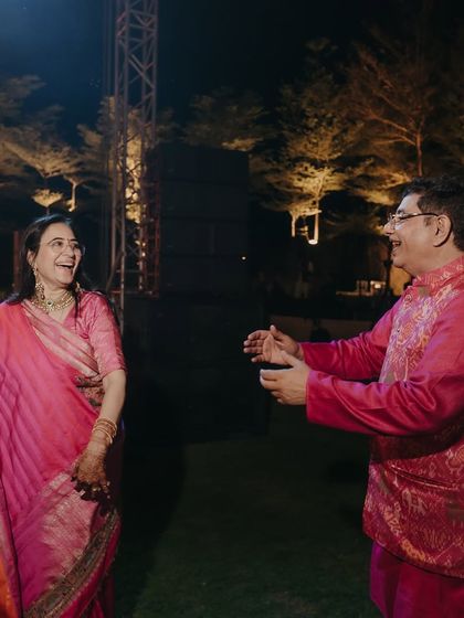 The parents sharing a dance at the sangeet. Their coordinated pink outfits are not just about matching colors but about celebrating their journey together as they watch their child get married.