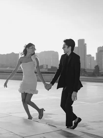 A candid, joyful moment captured in black and white against the Baku city skyline. The couple's movement and happiness create a dynamic and authentic image of their love.