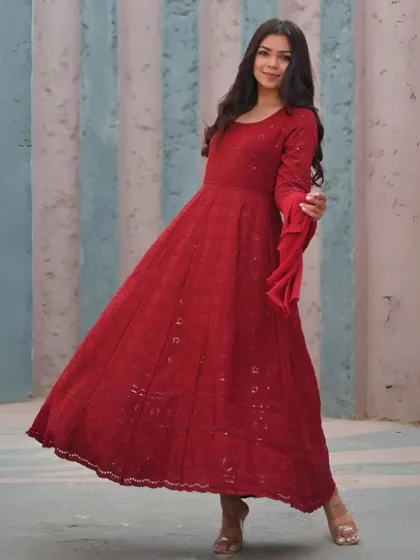 A floor-length red Anarkali suit with delicate embroidery. This is a timeless, elegant design that is perfect for celebrations and can be custom-made to your measurements.