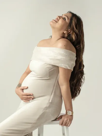 A beautiful three quarter portrait of a mom to be, basking in the light. Her joyful expression and the way she holds her bump radiate pure happiness.