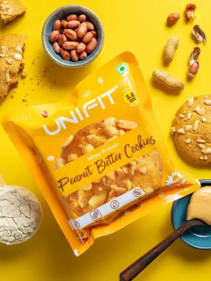 A vibrant top-down shot of Unifit's whey protein peanut butter cookies, showcasing the product packaging alongside its core ingredients for a clean e-commerce look.
