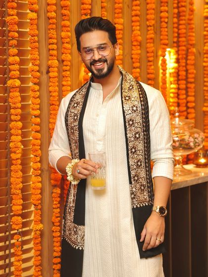 A client dressed for Diwali in a classic off-white kurta. The look is elevated by a stunning black stole with intricate, traditional embroidery, blending simplicity with festive grandeur.