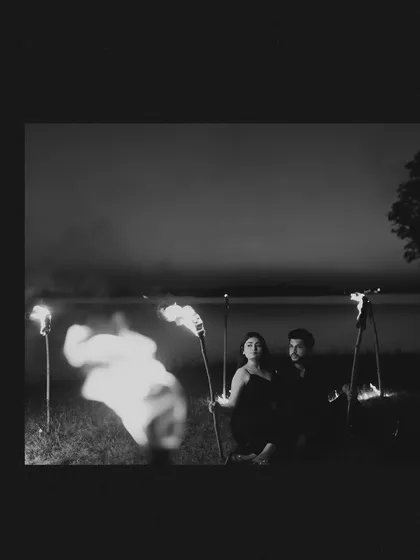 A moody black and white pre-wedding photo, using fire and slow shutter speed to create a ghostly, artistic effect.