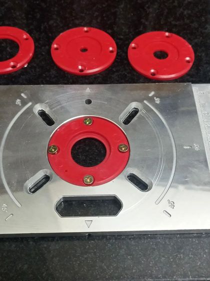 A close-up of the aluminum router plate and insert rings. This setup allows for quick changes of router bits and provides a solid, flat surface for working.