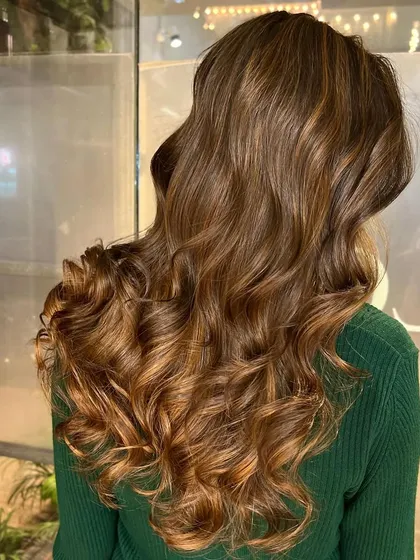 A beautiful example of a soft cinnamon brown color, styled with bouncy waves to showcase the rich tones.