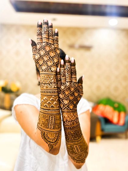 A playful pose highlighting the full length of the lotus-themed bridal henna.