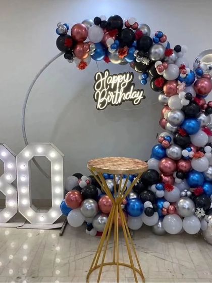 A 30th birthday setup with a multi-colored balloon arch, a neon sign, and large "30" marquee numbers.
