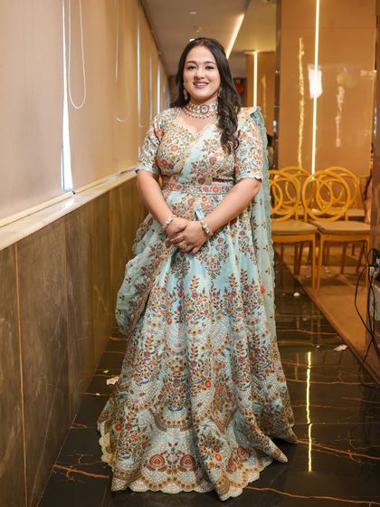 A full-length shot of the client in her floral lehenga, looking happy and confident.