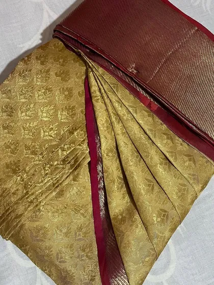 A gold brocade saree with a maroon border, perfect for special occasions.