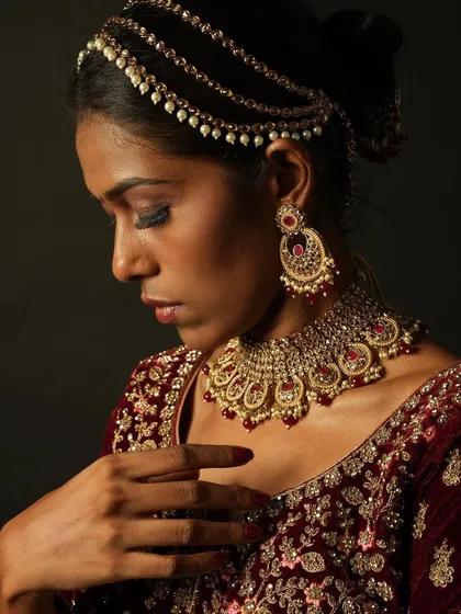 A close-up profile view, showing the details of the traditional jewelry and the clean, well-blended makeup.