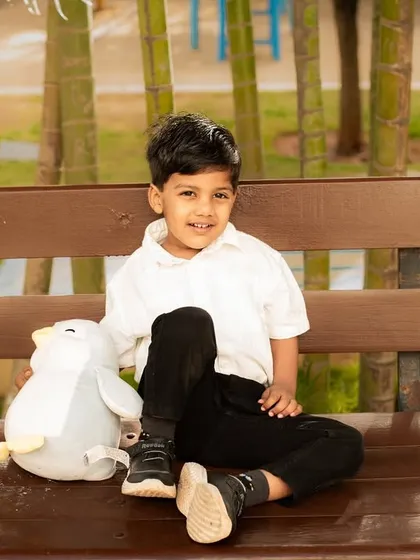 A relaxed portrait of a boy sitting on a bench with his favorite stuffed animal during an outdoor photoshoot.