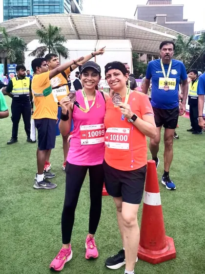Two athletes proudly showing off their finisher medals. The sense of accomplishment is shared.