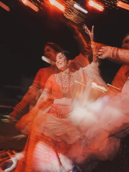 An artistic motion-blur shot of the bride dancing, capturing the movement and vibrant colors of the Sangeet night in an abstract and beautiful way.