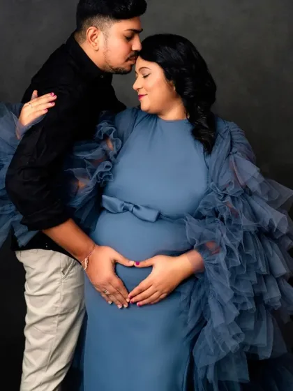 A loving embrace captured in this couple's portrait, with the partner's hands forming a heart on the baby bump.