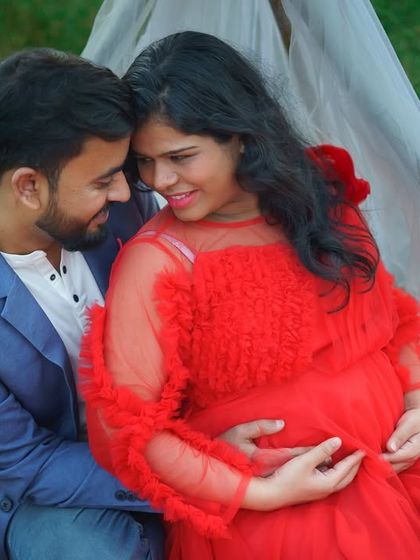 An intimate close-up from an outdoor maternity session. The couple shares a quiet moment, surrounded by nature, with the mother-to-be glowing in a vibrant red gown. These are the simple, heartfelt memories I love to capture.