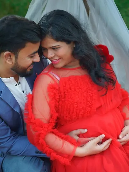 An intimate close-up from an outdoor maternity session. The couple shares a quiet moment, surrounded by nature, with the mother-to-be glowing in a vibrant red gown. These are the simple, heartfelt memories I love to capture.