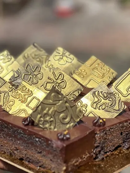 Our classic dark chocolate cake, decorated with intricate golden chocolate pyramids for a touch of luxury.