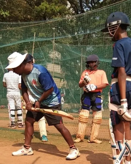 Demonstrating the correct batting stance to a young player. Balance and a steady head position are crucial for judging the ball and playing effective shots.
