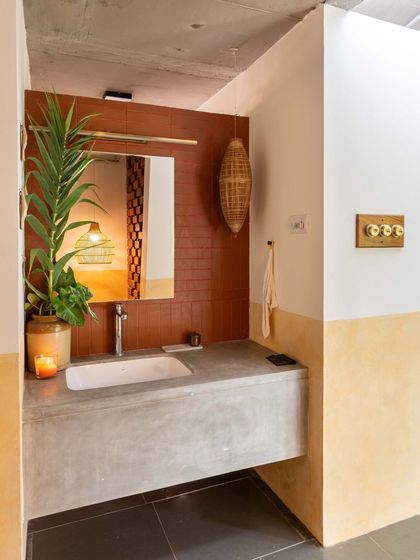 The powder room features a floating concrete vanity and a terracotta tile accent wall. The use of natural materials and warm lighting creates an earthy and welcoming atmosphere even in the smallest of spaces.
