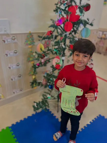 A student proudly holds up the Christmas stocking he decorated.