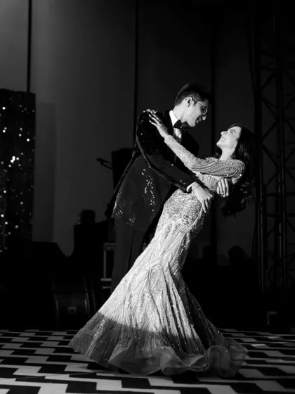 The first dance, captured in a dramatic black and white frame. The checkered floor and stage lights add a touch of old Hollywood glamour to this classic, romantic moment.