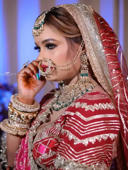A side profile of the bride in her pink lehenga, highlighting the details of her nath and earrings.