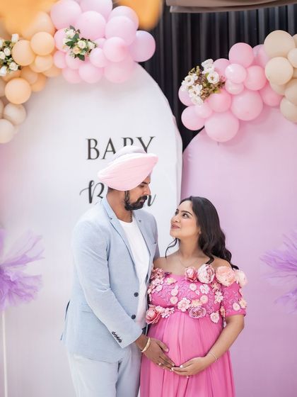 A candid moment of love and anticipation at their "Baby in Bloom" themed baby shower. The couple gazes at each other, surrounded by beautiful decorations and the love of their family and friends.