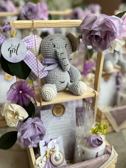 Welcoming a baby girl with a touch of handmade charm. This custom announcement hamper, in a lovely lavender theme, features a hand-crocheted elephant toy, a personalized announcement card, and other delicate keepsakes.
