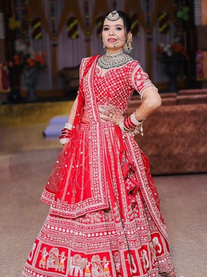 A confident pose from the bride in her stunning red lehenga with elephant motifs. The makeup is kept classic with a bold red lip.