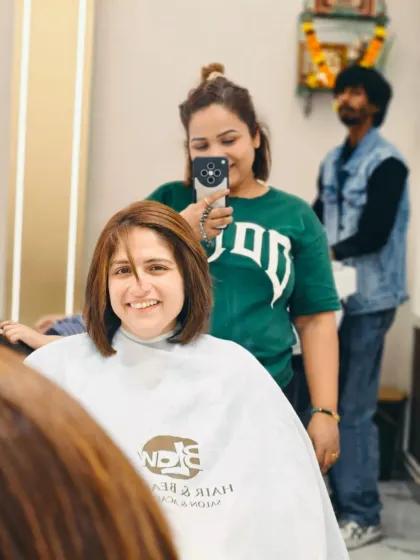 A mirror selfie with a client, showing off her new look. You can see our salon's cape and branding in the reflection.