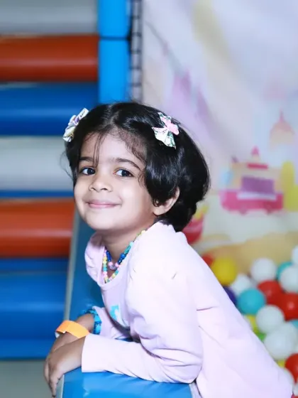 A lovely portrait of a young girl enjoying the party from the side of the ball pit. Her gentle smile is a beautiful contrast to the high energy of the play area.