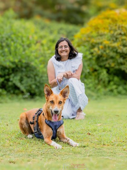 A lovely outdoor portrait of Coco and her mom. The focus is on the pet, but the owner's happy presence in the background completes the story.