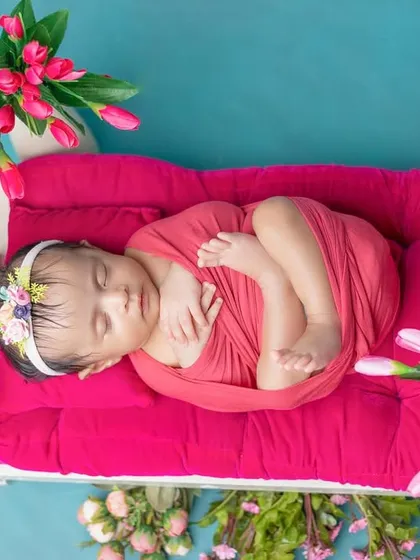 A top-down view of the baby swaddled on a tiny pink bed, a perfect princess pose.