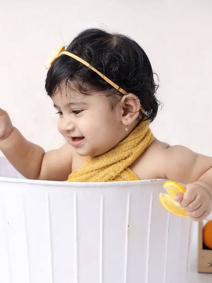 This little girl is having fun playing with toy lemons in our white bathtub setup. These sessions are full of smiles and natural expressions.