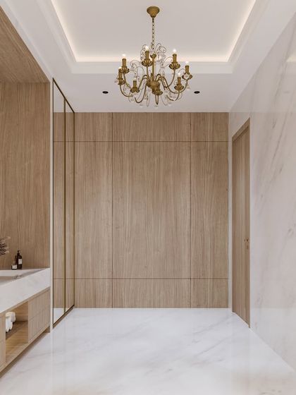 This view of the white marble bathroom highlights the wood-panelled wall, which adds warmth and texture, preventing the all-white space from feeling cold.
