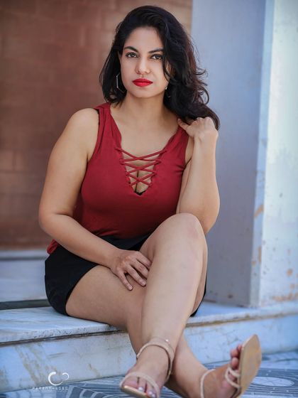 A classic and elegant seated portrait. The simple setting allows her confident expression and the bold red of her top to be the focus.