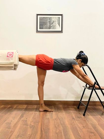 Using a chair and blankets to support the lifted leg in Virabhadrasana III (Warrior III) helps to build strength and stability. This modification allows the student to hold the pose longer and refine the alignment of the hips and spine.