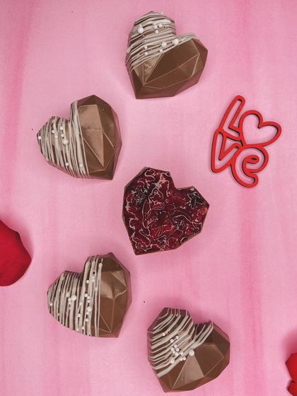 Love is sweet, and our heart-shaped chocolates make it even sweeter. These geometric chocolate hearts, some filled with jam and others drizzled with white chocolate, are perfect for celebrating Valentine's Day, anniversaries, or just because.
