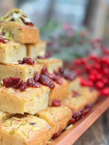 A tray of delicious pistachio and cranberry tea cakes, stacked high and ready to be served at a Christmas party.