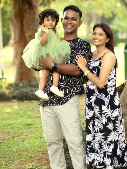 A classic family portrait in the park, with parents and their young daughter smiling together, creating a timeless memory.