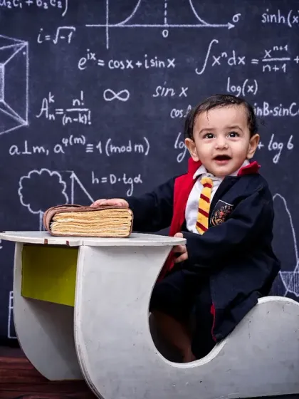 A wide shot of the Harry Potter themed photoshoot, showing the little wizard at his desk with a globe, books, and vintage cameras. The detailed set creates a magical atmosphere for the portrait.