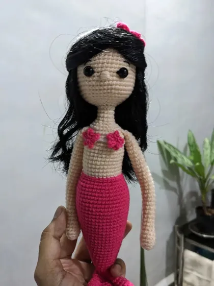 The mermaid doll held in hand to show its size.